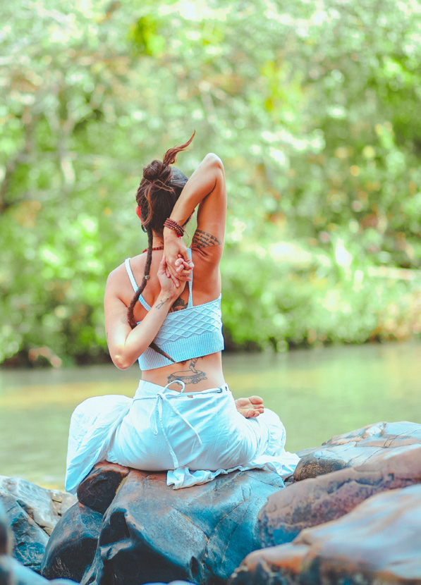 woman sitting on stones doing yoga